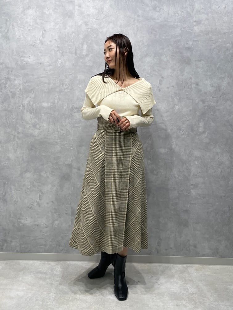 ブラック系のブーツ、ベージュ系のスカート、ホワイト系のニット/セーターを着用したレディースの秋コーディネートの2枚目の写真