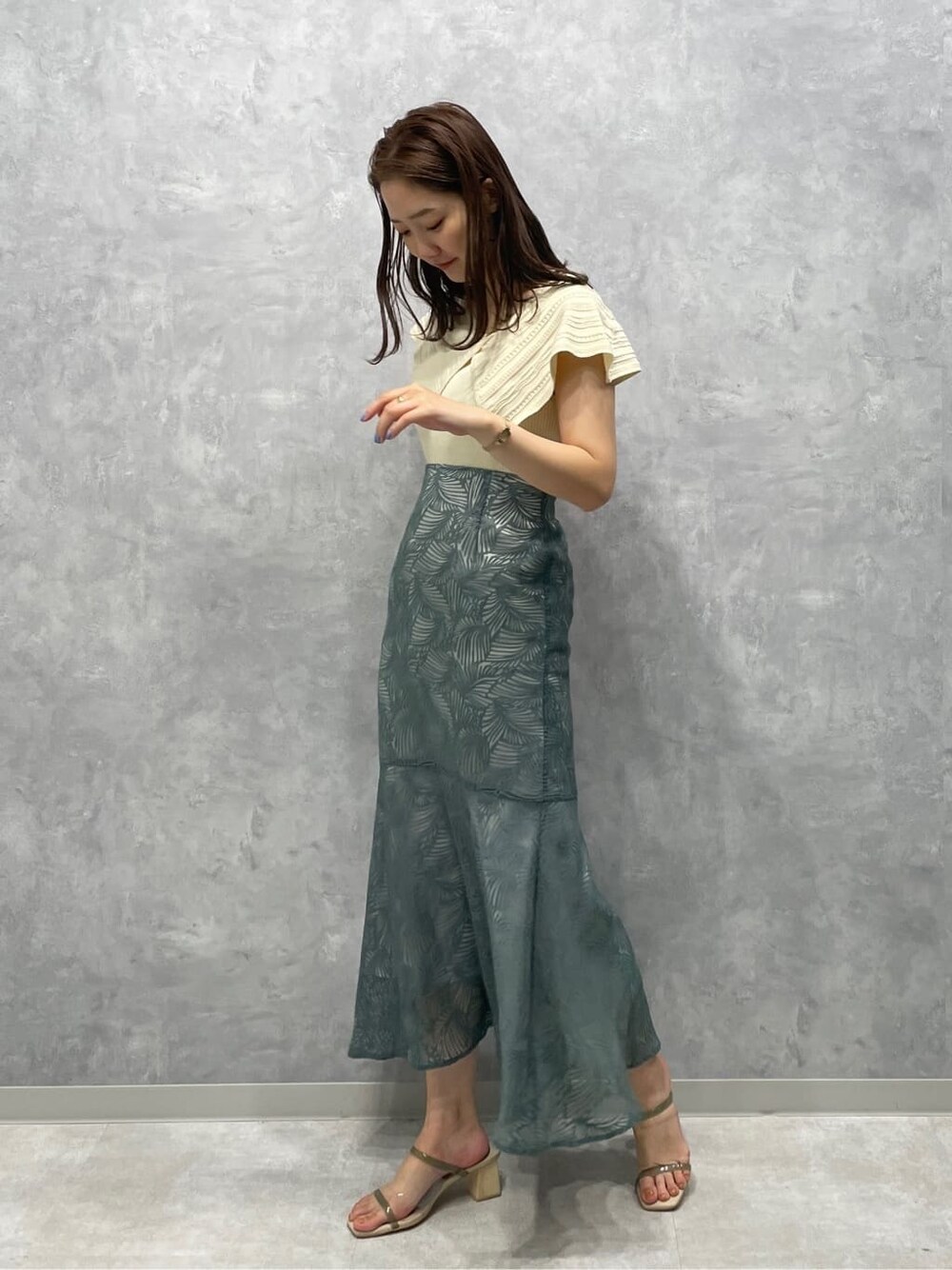 グリーン系のサンダル、ブルー系のスカート、ホワイト系のニット/セーターを着用したレディースの夏コーディネートの2枚目の写真