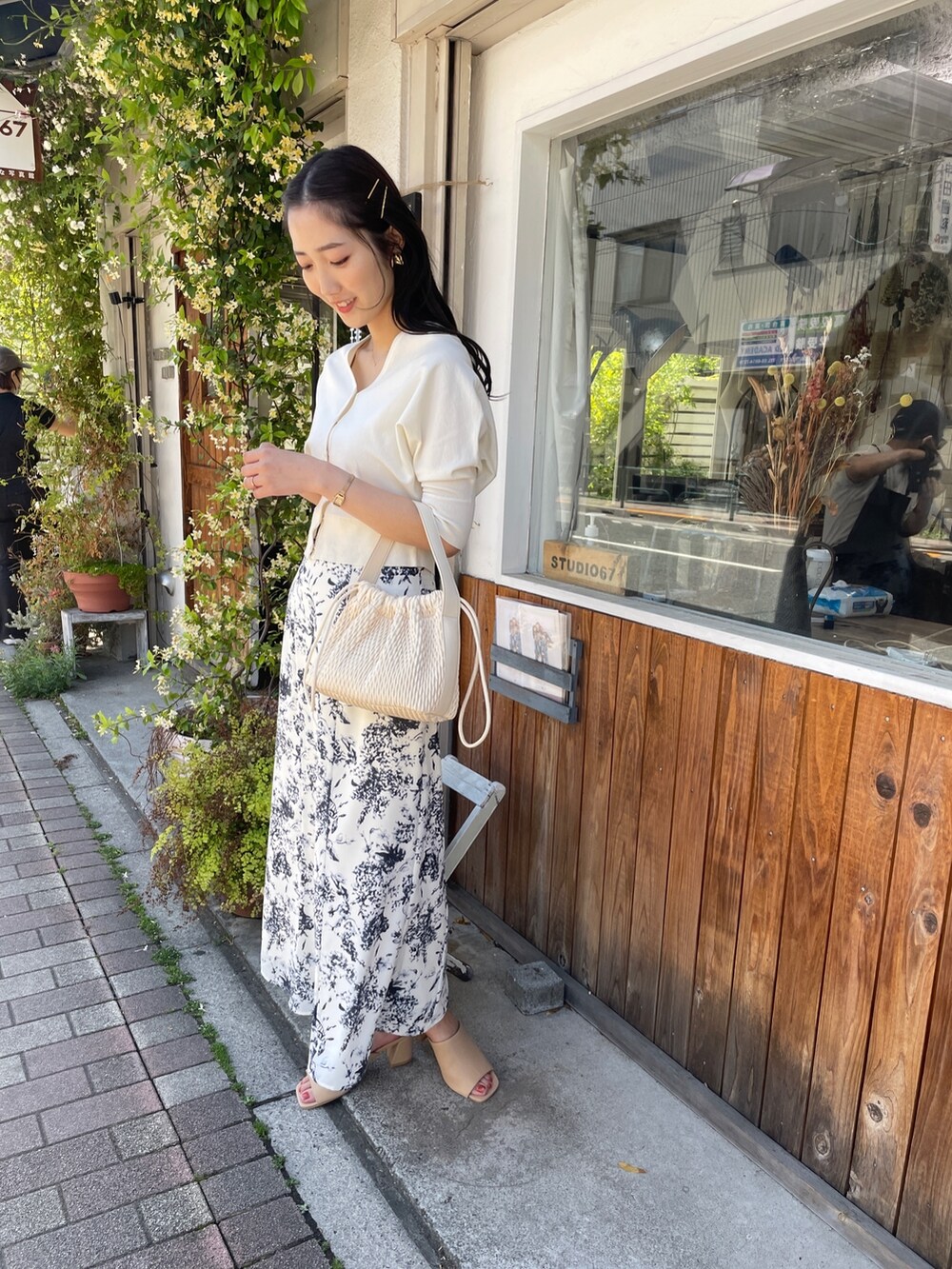 ベージュ系のハンドバッグ、ホワイト系のカーディガン/ボレロ、ブルー系のスカートを着用したレディースの春コーディネートの2枚目の写真