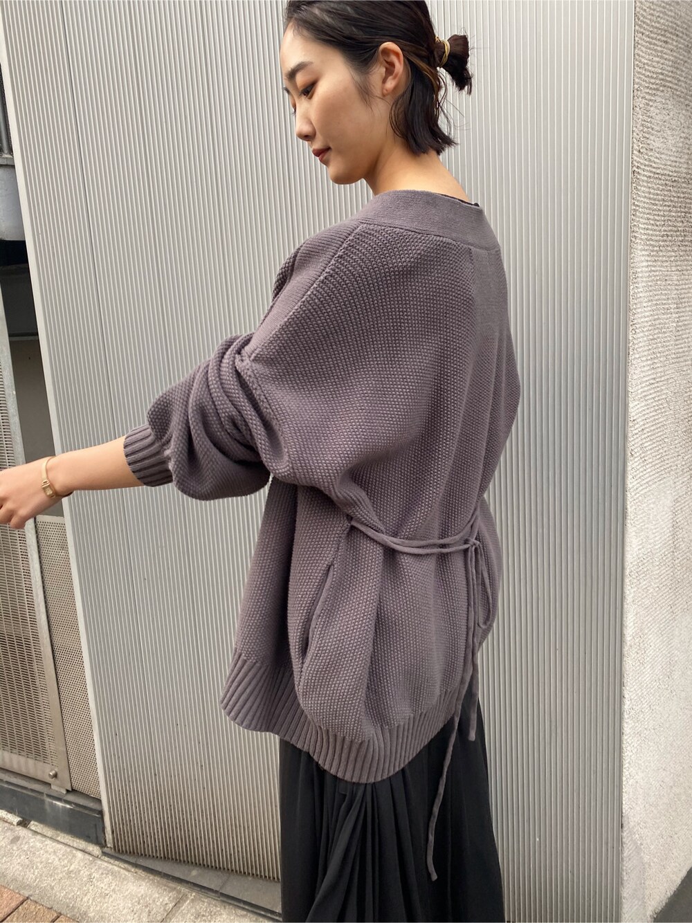 ブラウン系のパンプス、グレー系のカーディガン/ボレロ、ブラック系のワンピースを着用したレディースの春コーディネートの2枚目の写真