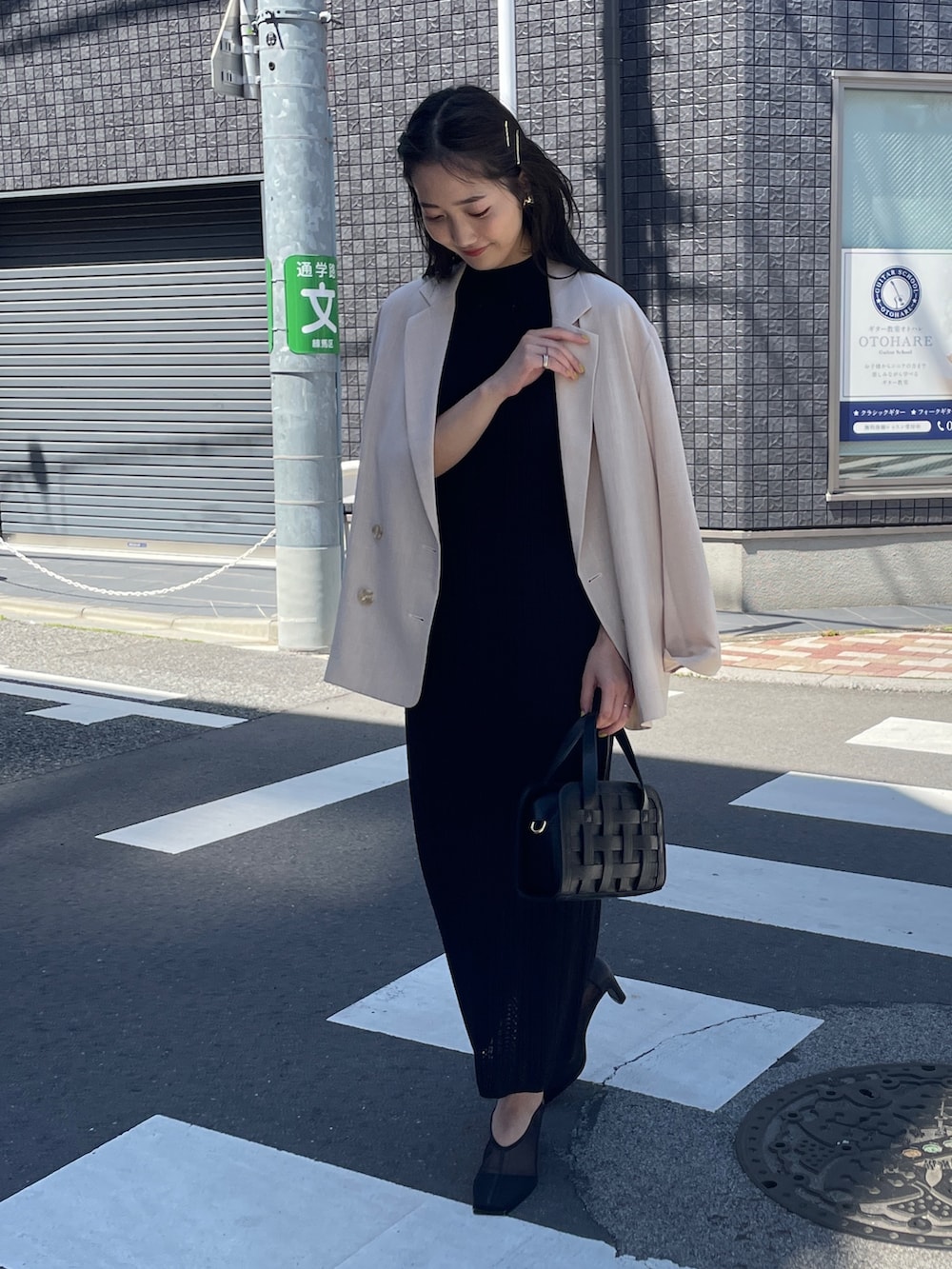 ブラック系のショルダーバッグ、ブラック系のワンピース、ベージュ系のテーラードジャケットを着用したレディースの春コーディネートの3枚目の写真