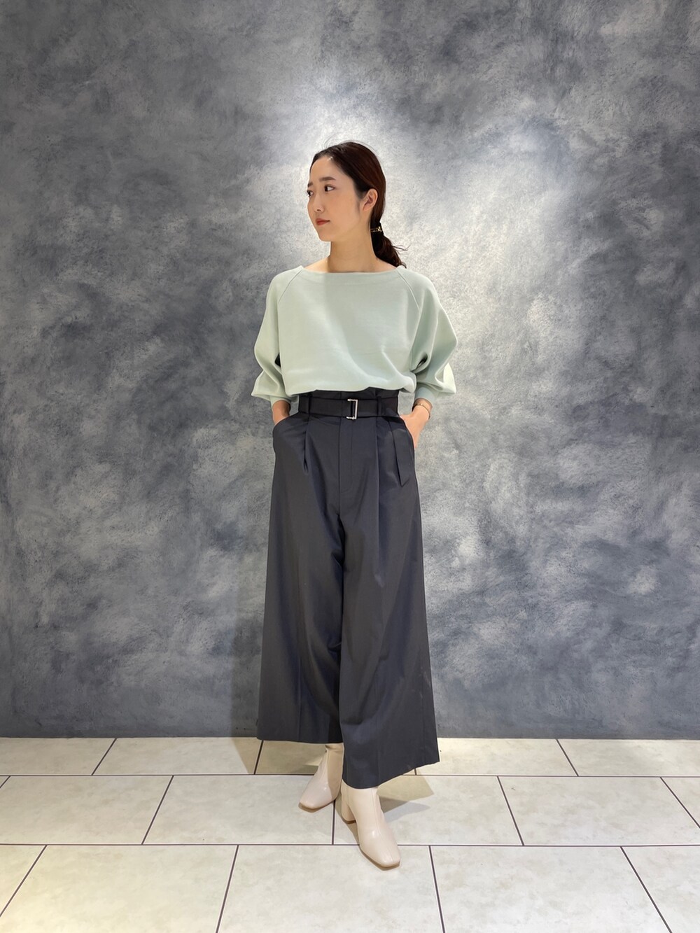 グレー系のその他パンツ、ホワイト系のブーツ、グリーン系のニット/セーターを着用したレディースの冬コーディネートの7枚目の写真