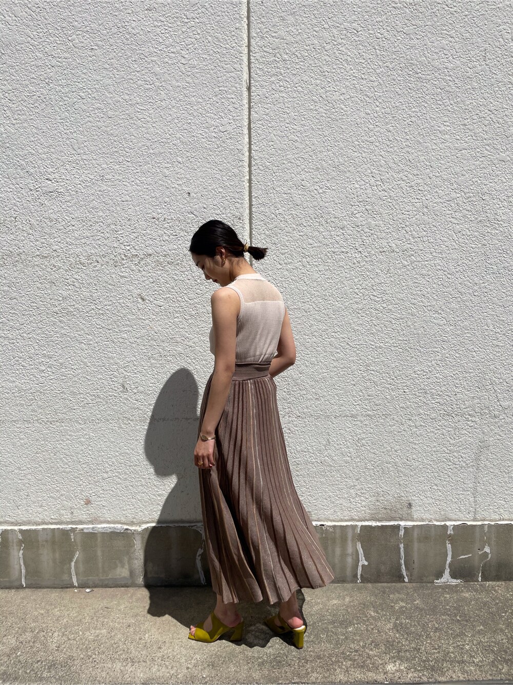 グリーン系のサンダル、ブラウン系のスカート、ホワイト系のニット/セーターを着用したレディースの春コーディネートの2枚目の写真