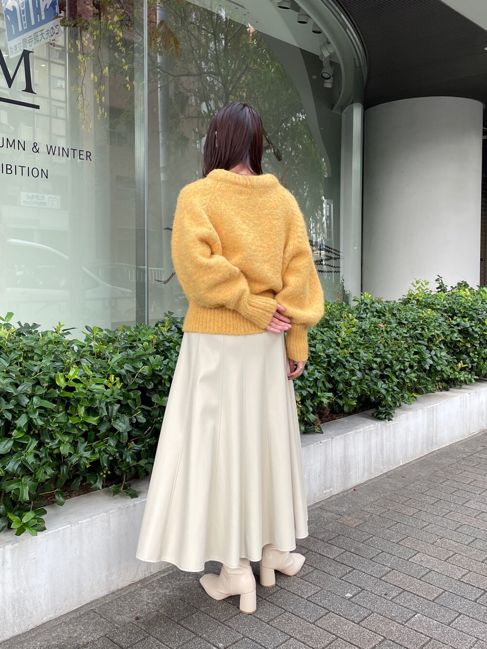 ホワイト系のブーツ、ホワイト系のスカート、イエロー系のニット/セーターを着用したレディースの秋コーディネートの4枚目の写真