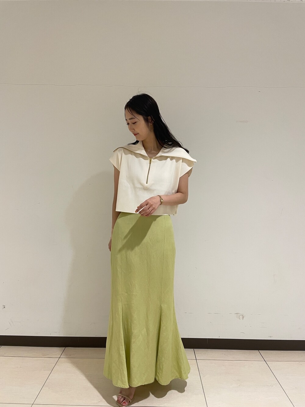 ホワイト系のニット/セーター、ベージュ系のサンダル、グリーン系のスカートを着用したレディースの春コーディネートの3枚目の写真