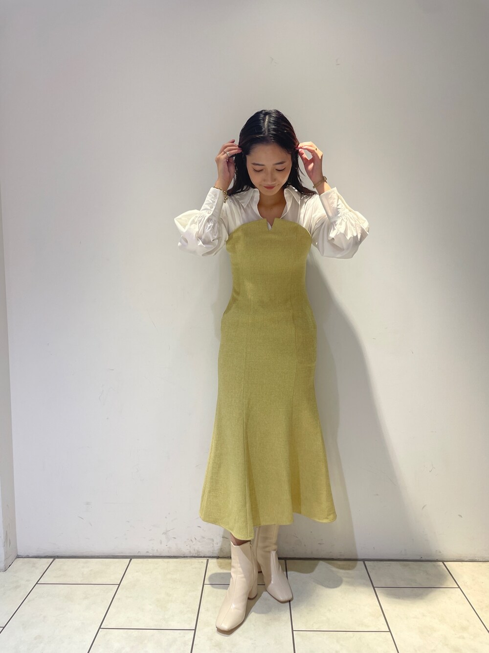 イエロー系のワンピース、ホワイト系のブーツを着用したレディースの秋コーディネートの2枚目の写真