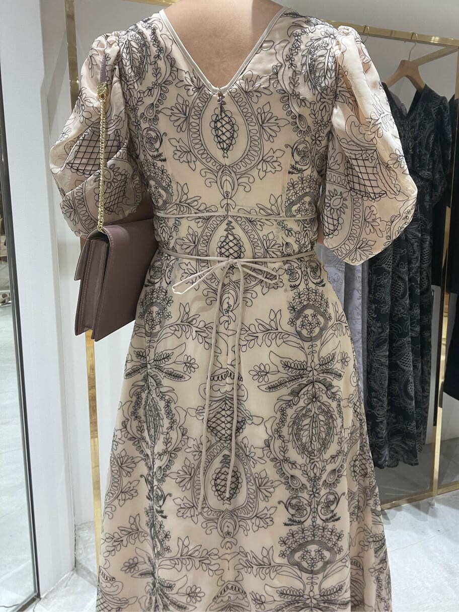 ベージュ系のドレス、ピンク系のパンプス、ピンク系のクラッチバッグを着用したレディースの春コーディネートの6枚目の写真