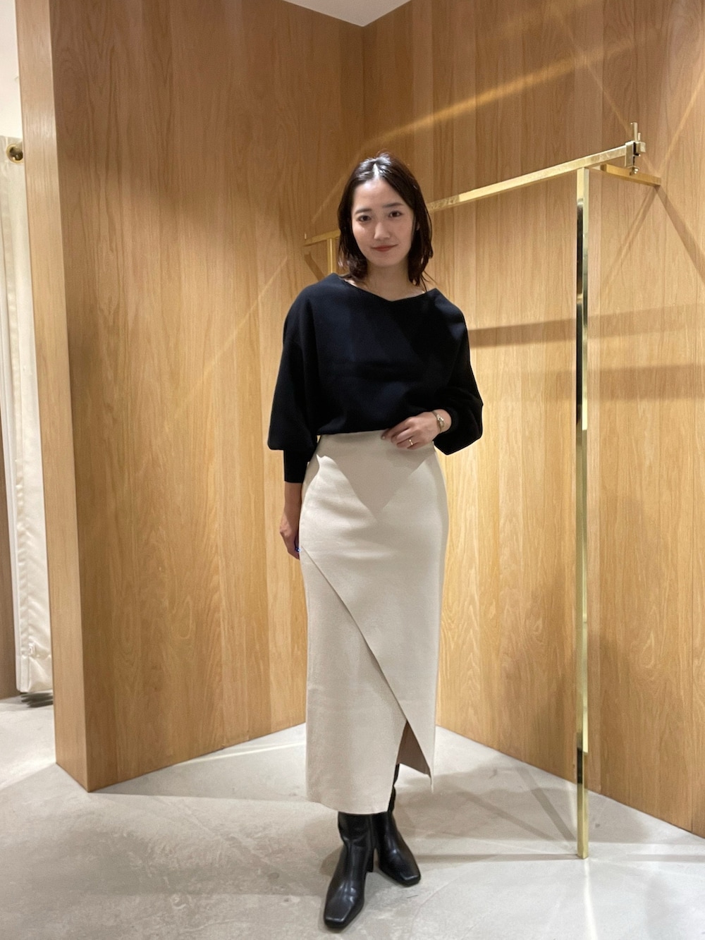 ホワイト系のスカート、ブラック系のニット/セーター、ブラック系のブーツを着用したレディースの秋コーディネートの4枚目の写真