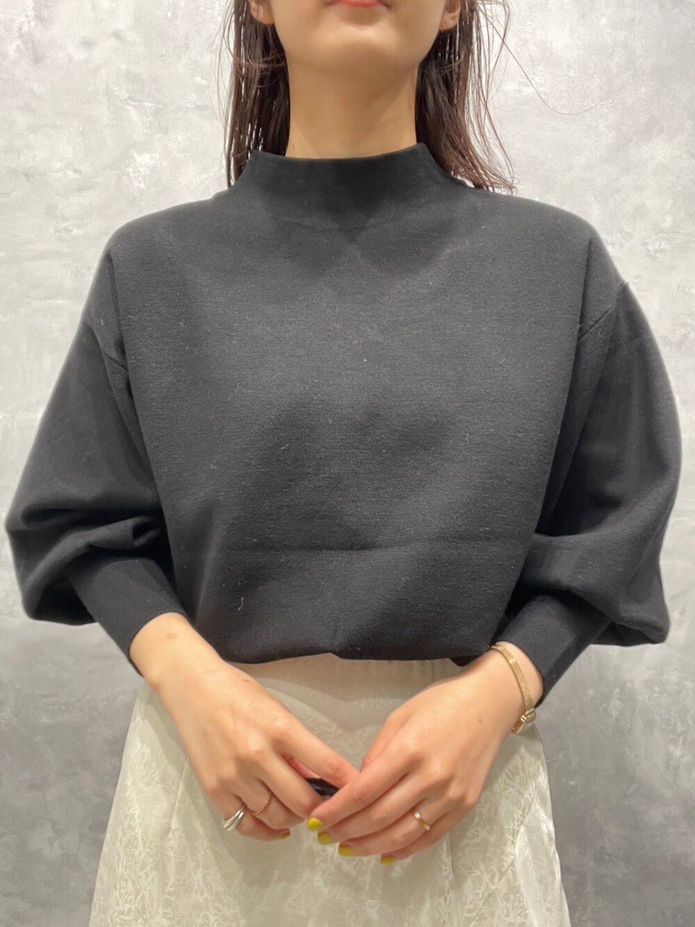 ブラック系のニット/セーター、ホワイト系のスカート、ベージュ系のブーツを着用したレディースの冬コーディネートの7枚目の写真