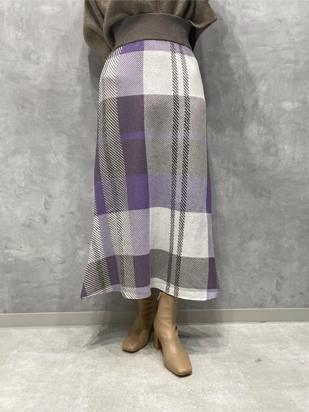 ベージュ系のブーツ、ベージュ系のカーディガン/ボレロ、パープル系のスカートを着用したレディースの秋コーディネートの9枚目の写真