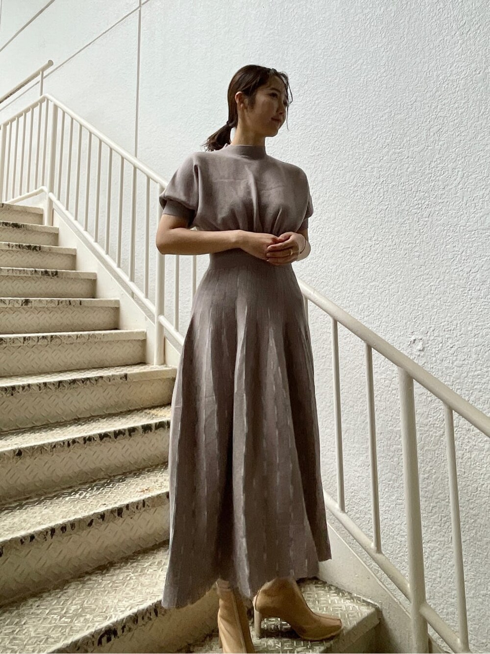 ベージュ系のトレンチコート、グレー系のワンピース、ベージュ系のブーツを着用したレディースの春コーディネートの6枚目の写真