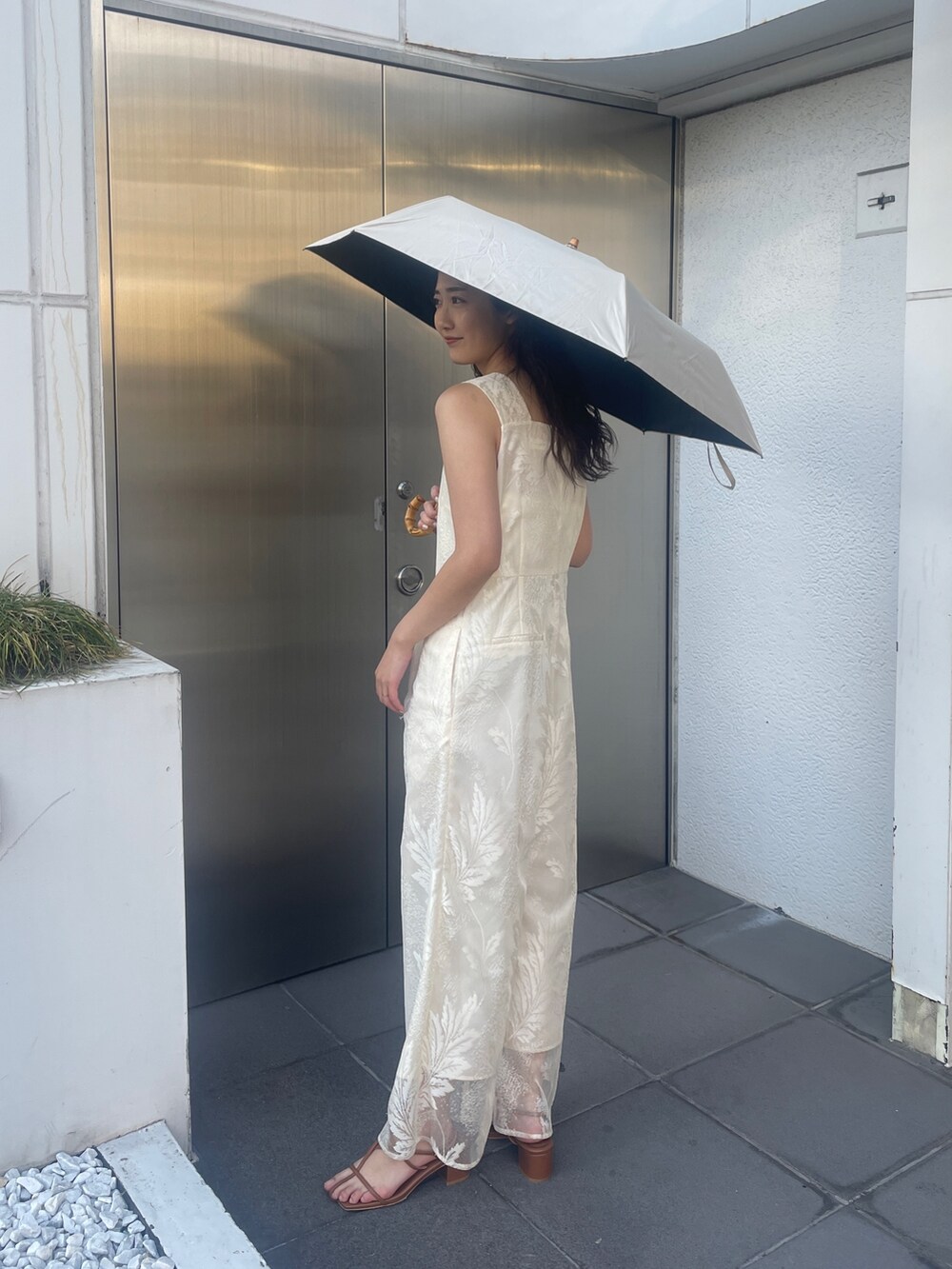 ブラウン系のサンダル、ホワイト系のつなぎ/オールインワン、ベージュ系の折りたたみ傘を着用したレディースの冬コーディネートの10枚目の写真