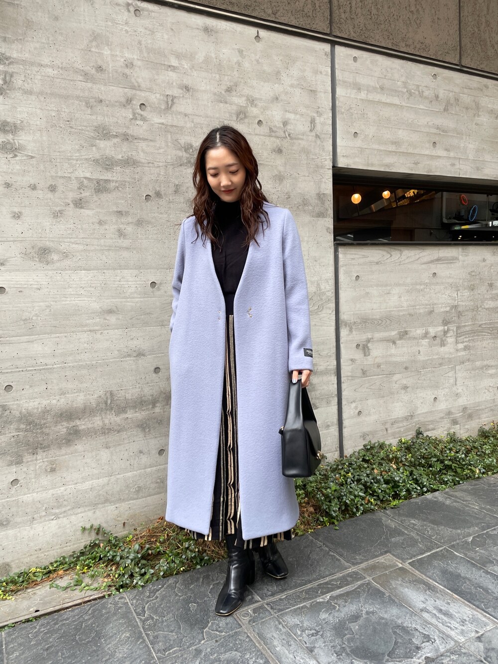 ブルー系のノーカラーコート、ブラック系のワンピース、ブラック系のブーツを着用したレディースの冬コーディネートの3枚目の写真