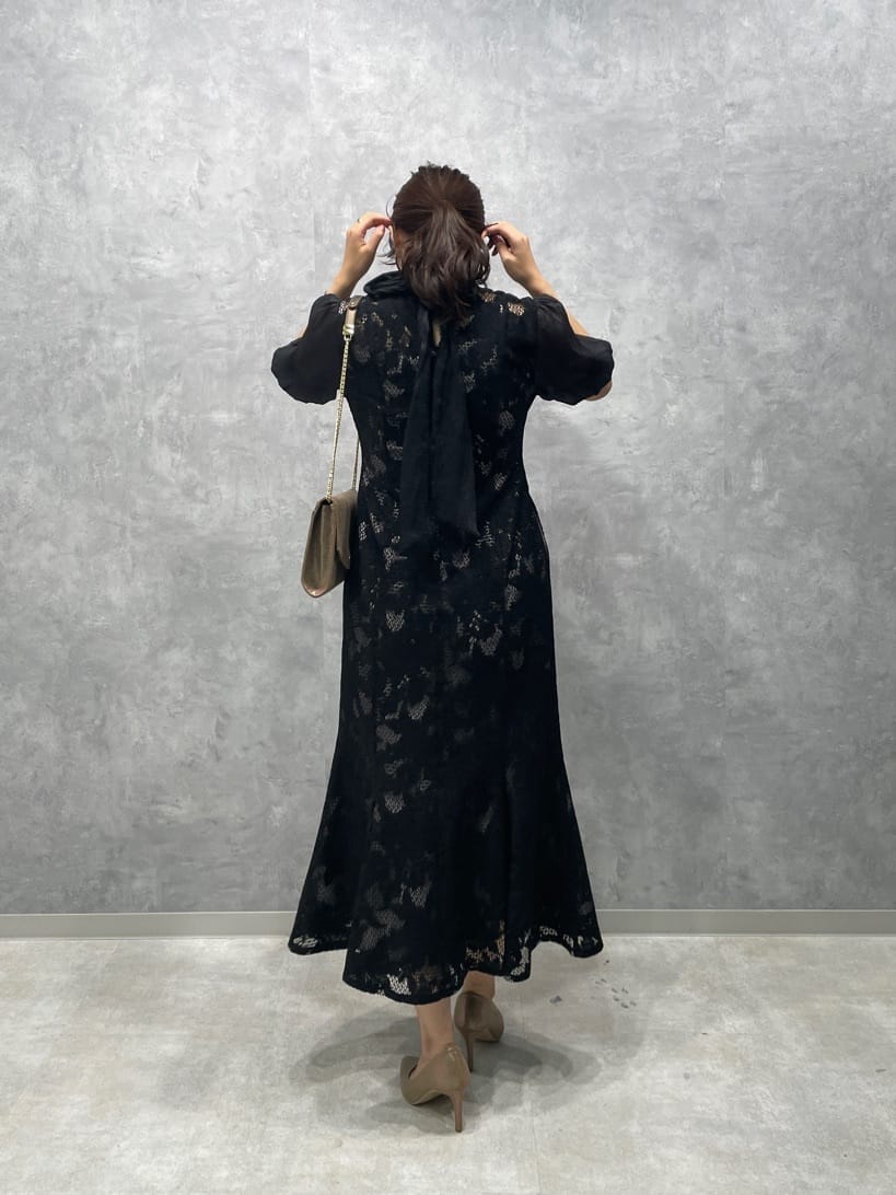 ゴールド系のパンプス、ゴールド系のクラッチバッグ、ブラック系のドレスを着用したレディースの秋コーディネートの6枚目の写真