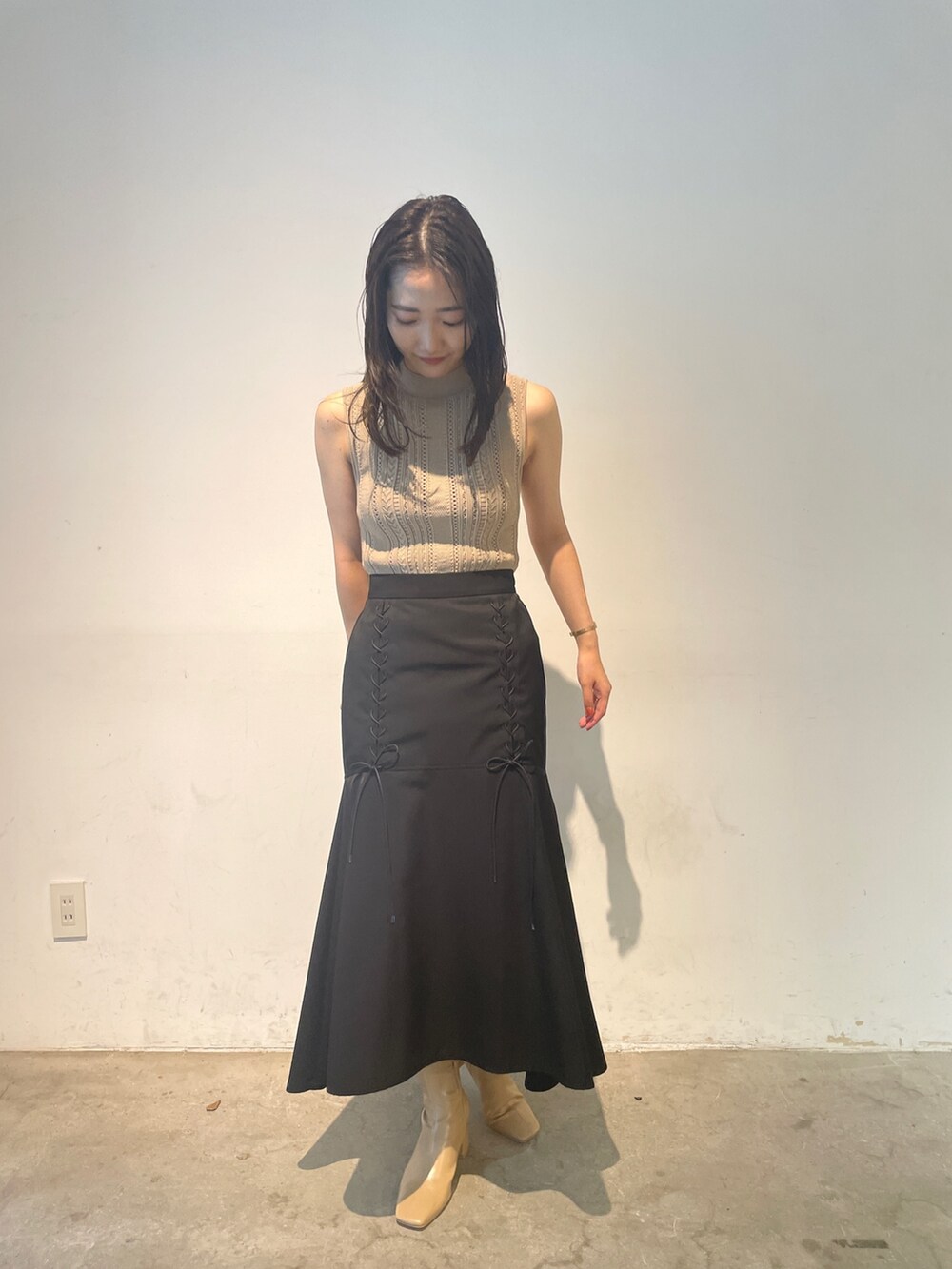 ベージュ系のニット/セーター、ベージュ系のブーツ、ブラック系のスカートを着用したレディースの夏コーディネートの4枚目の写真