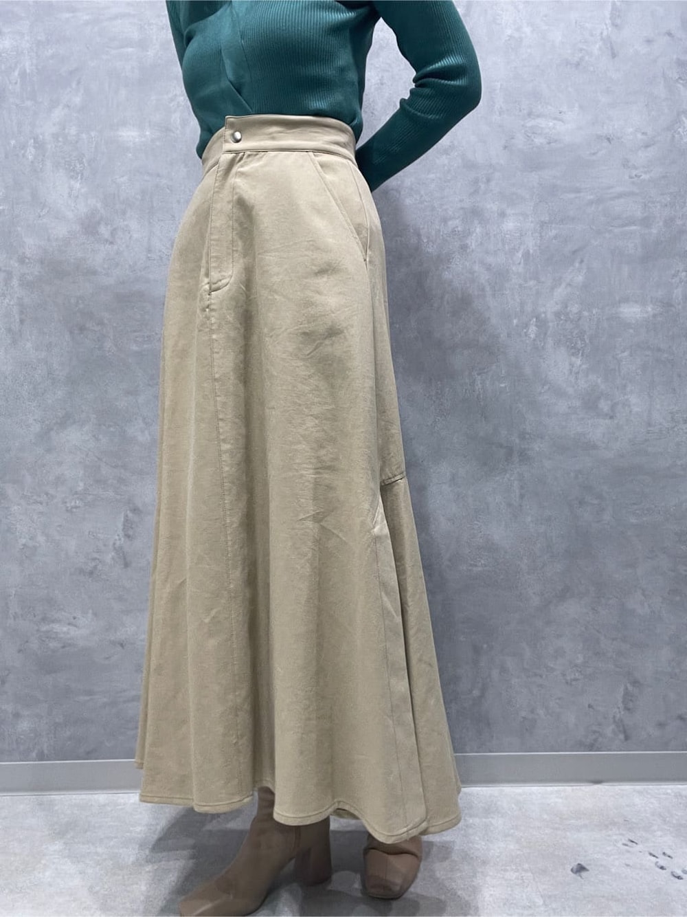 ベージュ系のスカート、ベージュ系のブーツ、グリーン系のニット/セーターを着用したレディースの夏コーディネートの9枚目の写真