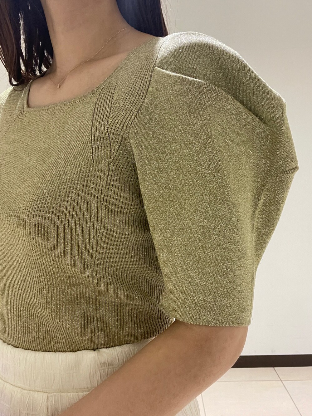 ホワイト系のスカート、グリーン系のニット/セーター、ブラック系のサンダルを着用したレディースの春コーディネートの7枚目の写真