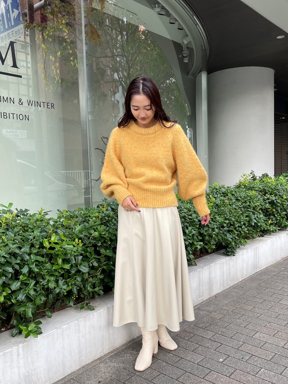 ホワイト系のブーツ、ホワイト系のスカート、イエロー系のニット/セーターを着用したレディースの秋コーディネートの2枚目の写真