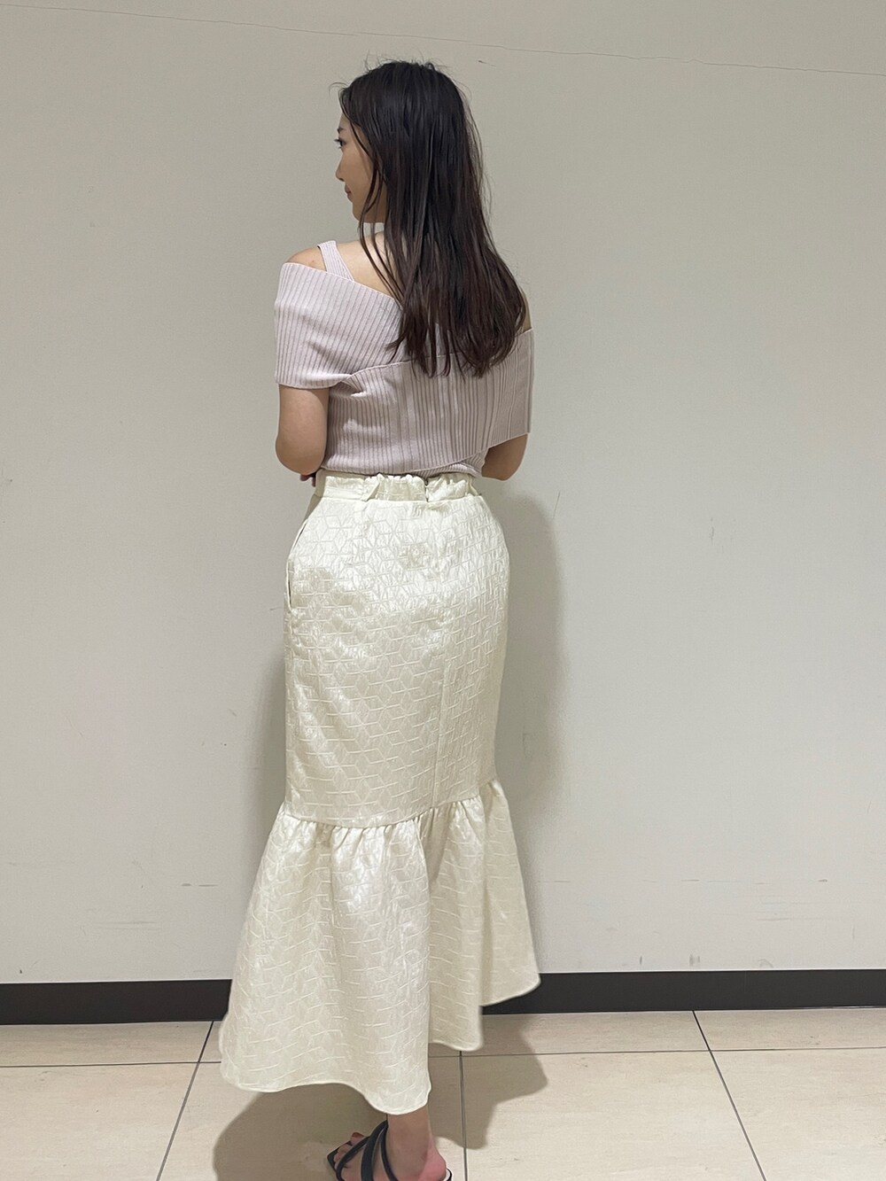 ホワイト系のスカート、ベージュ系のニット/セーター、ブラック系のサンダルを着用したレディースの春コーディネートの5枚目の写真