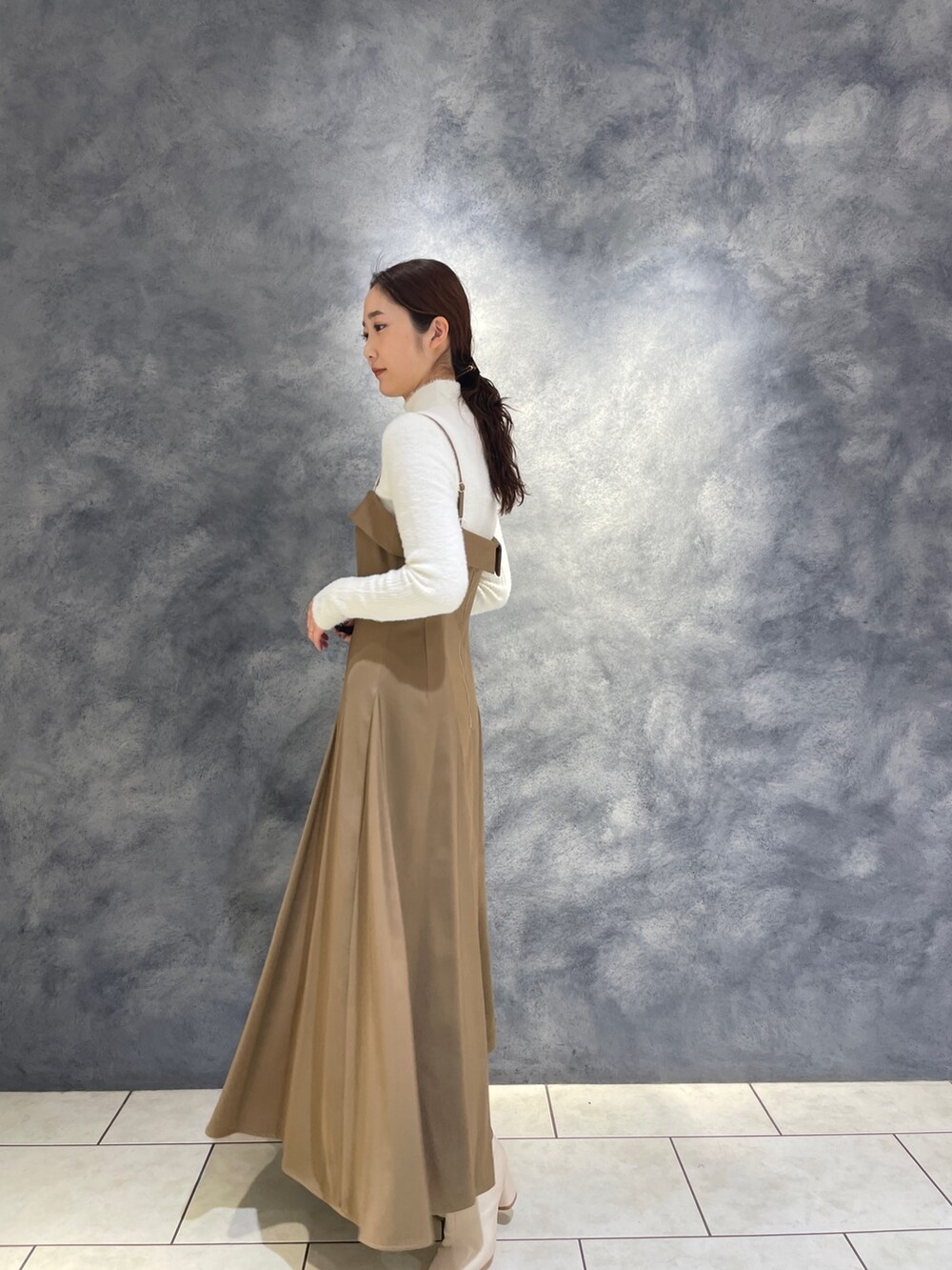 ベージュ系のワンピース、ホワイト系のニット/セーター、ホワイト系のブーツを着用したレディースの冬コーディネートの7枚目の写真