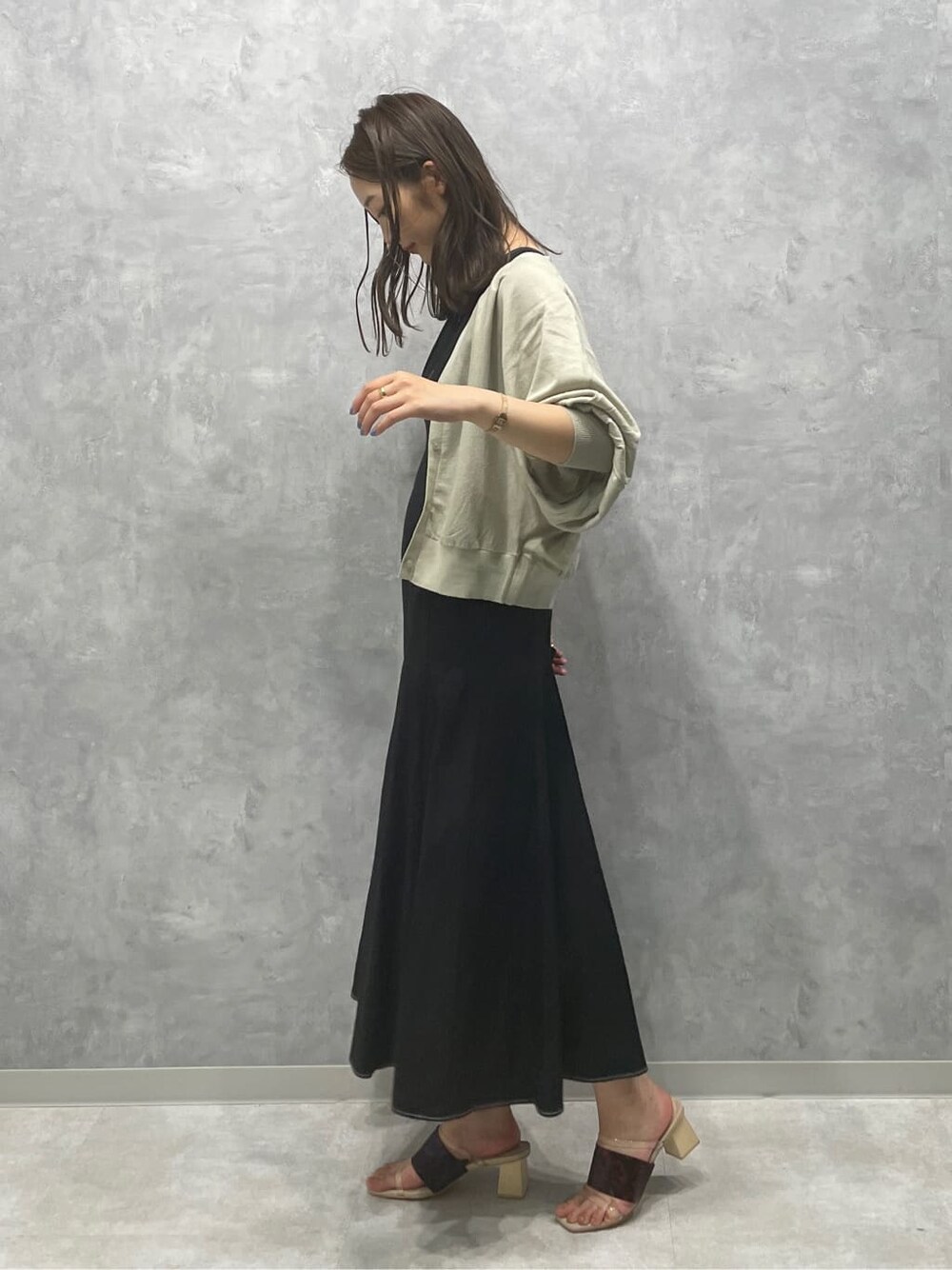 ブラウン系のサンダル、グリーン系のカーディガン/ボレロ、ブラック系のワンピースを着用したレディースの夏コーディネートの2枚目の写真