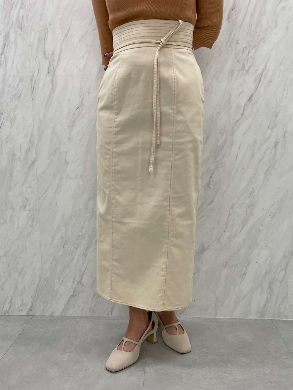 ホワイト系のパンプス、オレンジ系のニット/セーター、ホワイト系のスカートを着用したレディースの冬コーディネートの8枚目の写真