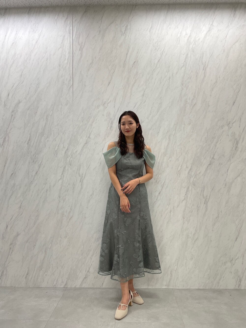 ホワイト系のパンプス、グリーン系のドレスを着用したレディースの冬コーディネートの4枚目の写真