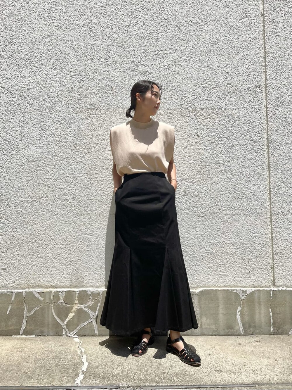 ブラック系のスカート、ベージュ系のニット/セーターを着用したレディースの夏コーディネートの2枚目の写真