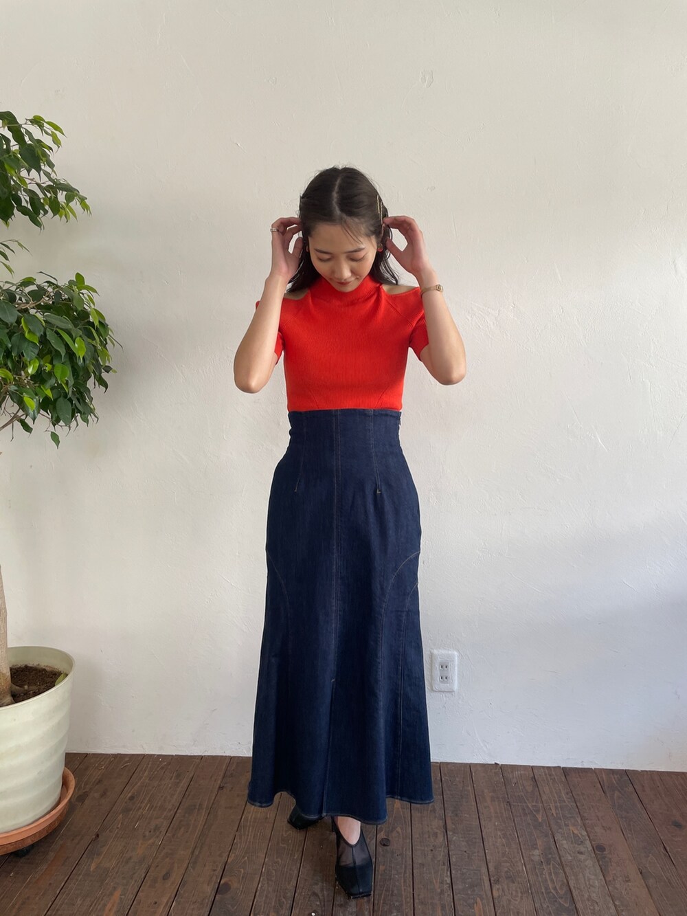 オレンジ系のニット/セーター、ブルー系のデニムスカート、ブラック系のパンプスを着用したレディースの春コーディネートの2枚目の写真