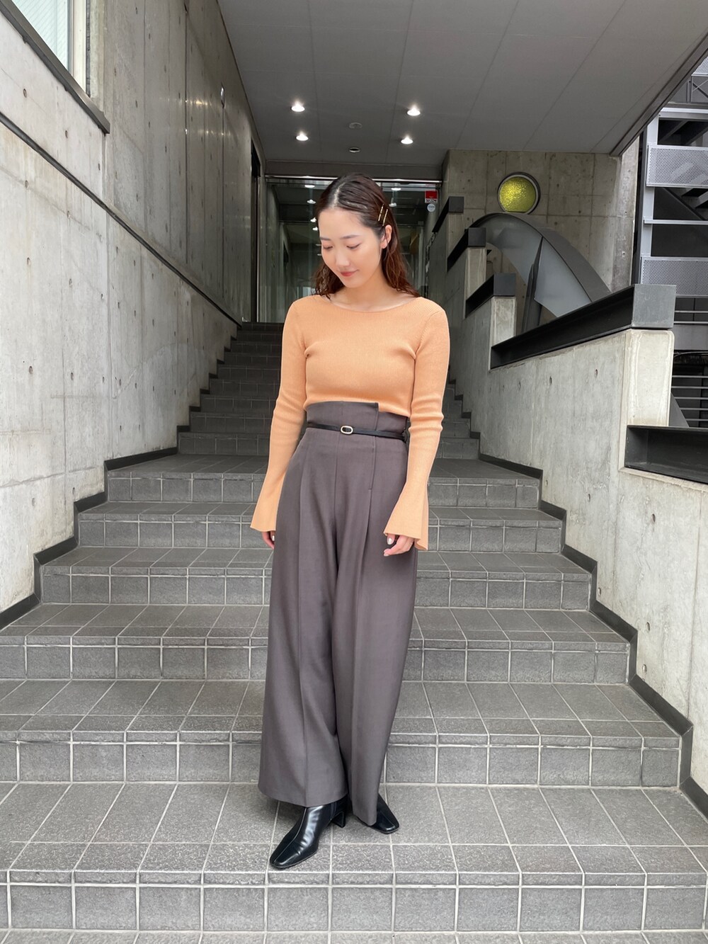 グレー系のその他パンツ、オレンジ系のニット/セーター、ブラック系のブーツを着用したレディースの秋コーディネートの5枚目の写真