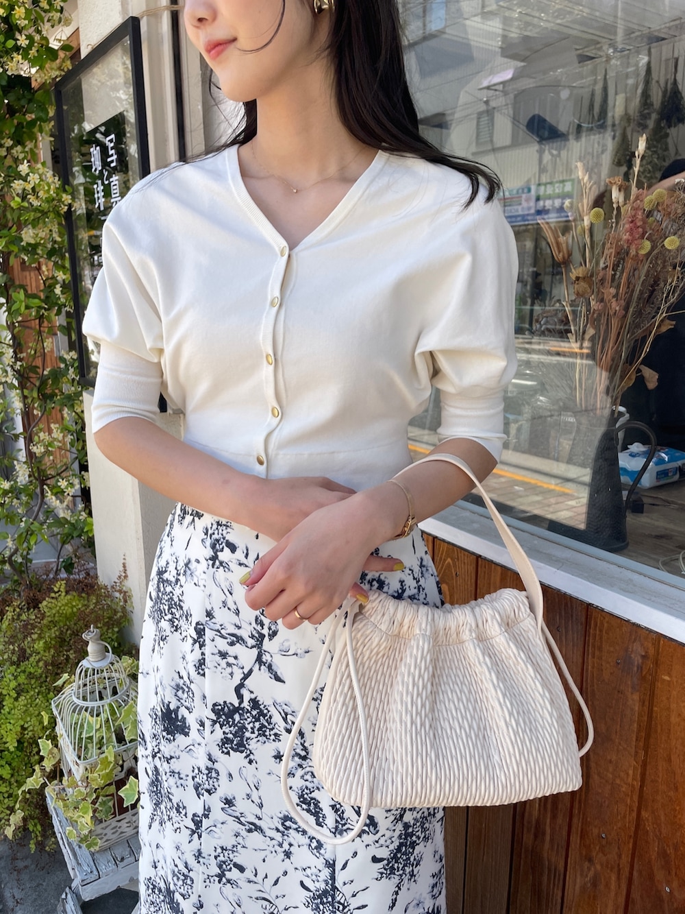 ベージュ系のハンドバッグ、ホワイト系のカーディガン/ボレロ、ブルー系のスカートを着用したレディースの春コーディネートの5枚目の写真