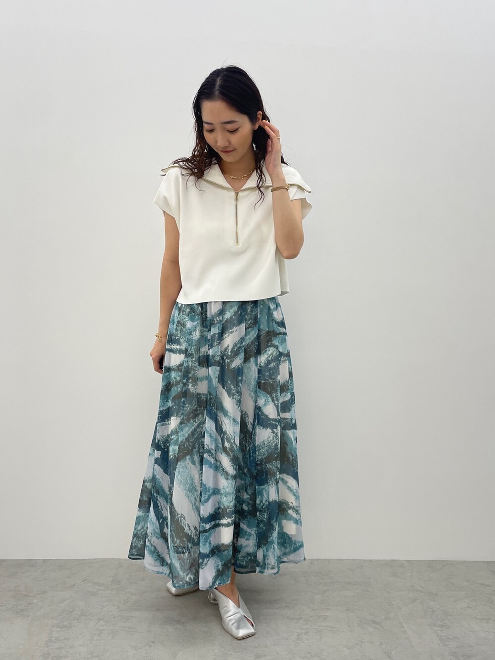 シルバー系のパンプス、ブルー系のスカート、ホワイト系のTシャツ/カットソーを着用したレディースの春コーディネートの4枚目の写真