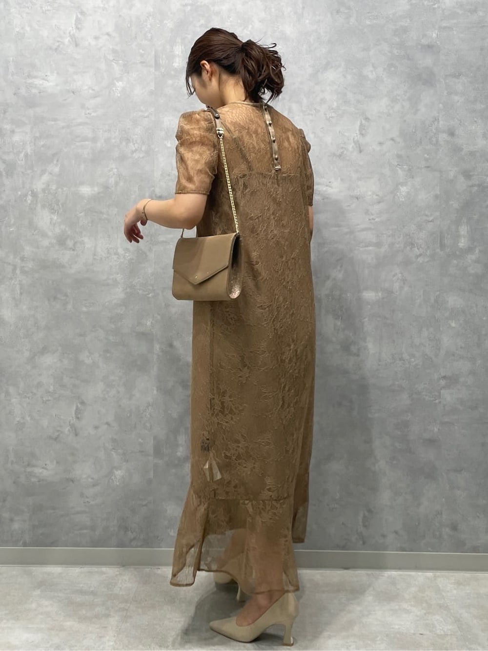 ゴールド系のクラッチバッグ、ベージュ系のパンプス、ベージュ系のドレスを着用したレディースの春コーディネートの2枚目の写真