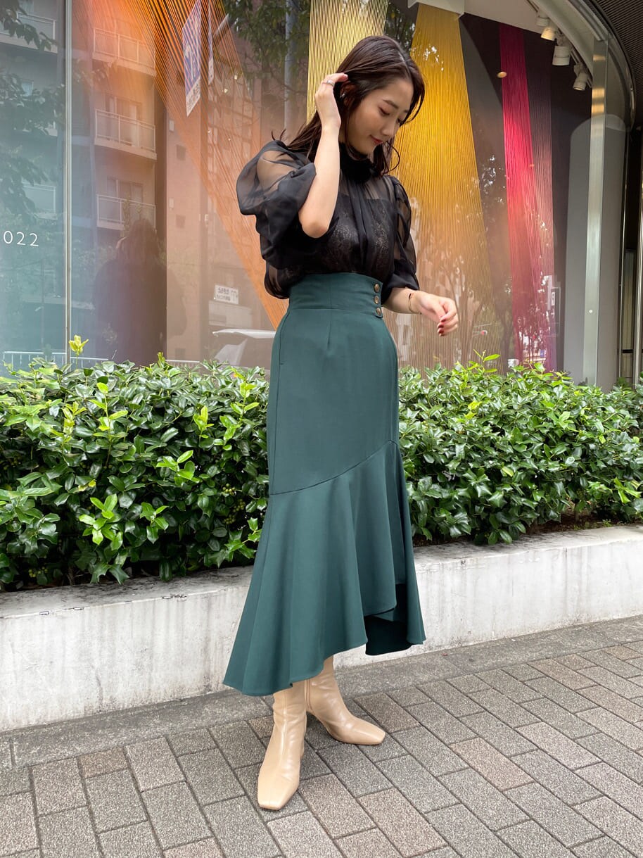 ベージュ系のトレンチコート、グリーン系のスカート、ベージュ系のトレンチコートを着用したレディースの秋コーディネートの5枚目の写真