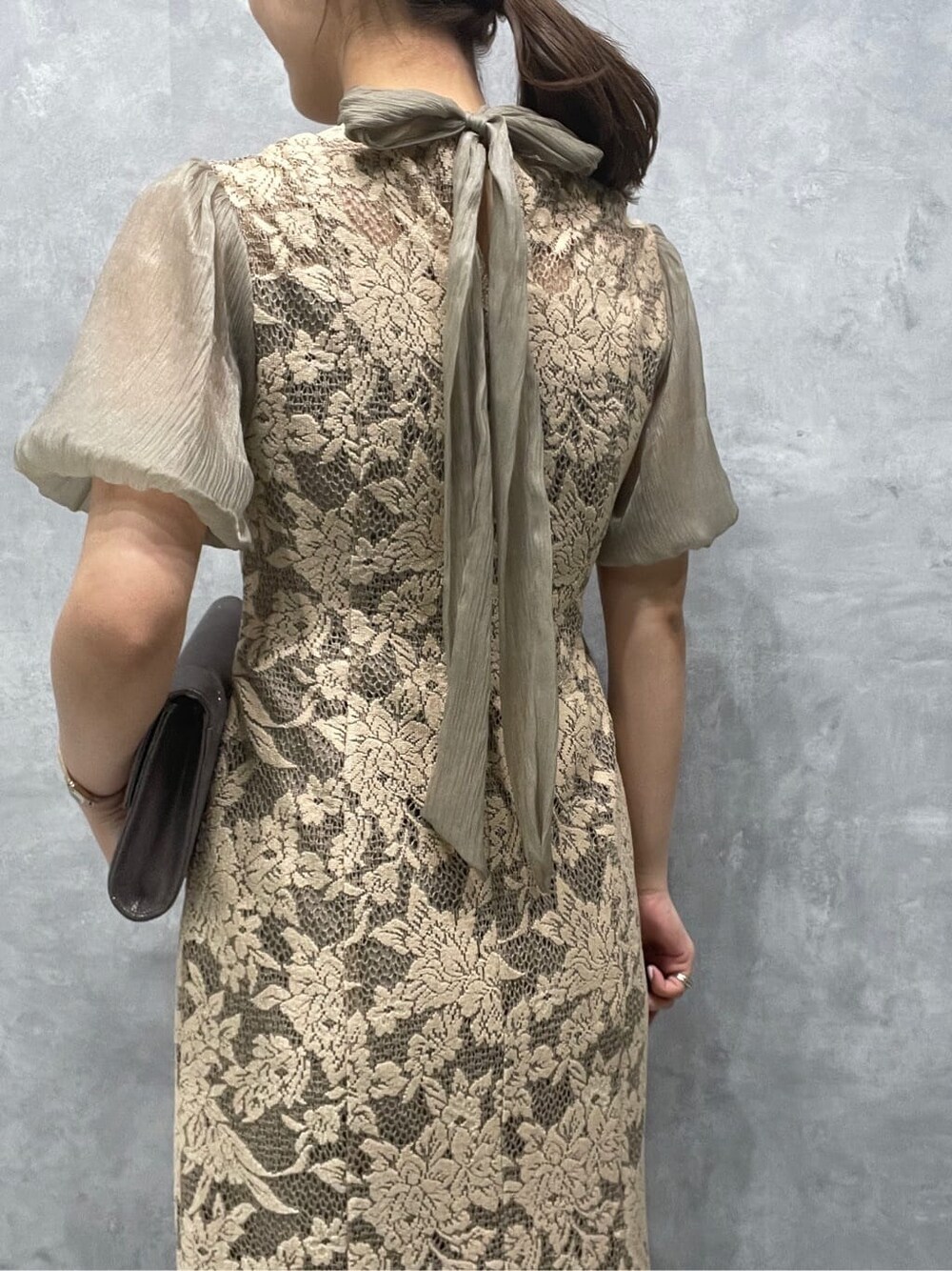 ベージュ系のドレス、シルバー系のパンプス、シルバー系のクラッチバッグを着用したレディースの夏コーディネートの7枚目の写真