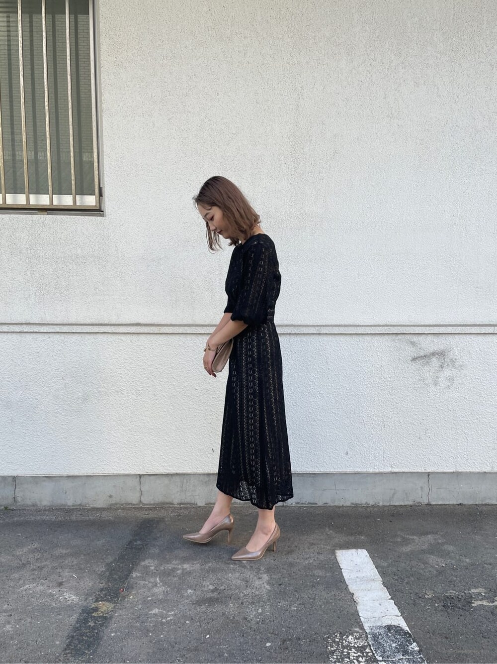 ゴールド系のパンプス、ゴールド系のクラッチバッグ、ブラック系のドレスを着用したレディースの冬コーディネートの2枚目の写真