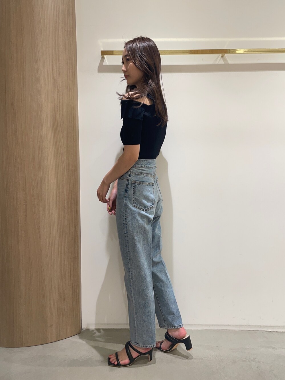 ブラック系のニット/セーター、ブラック系のサンダル、ブルー系のデニムパンツを着用したレディースの春コーディネートの4枚目の写真