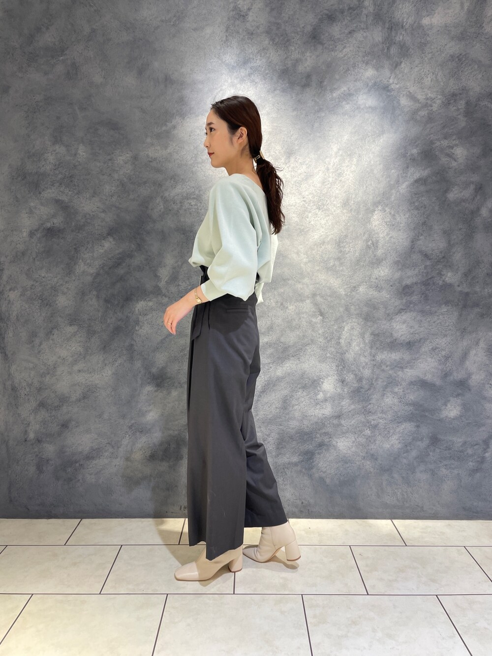 グレー系のその他パンツ、ホワイト系のブーツ、グリーン系のニット/セーターを着用したレディースの冬コーディネートの5枚目の写真