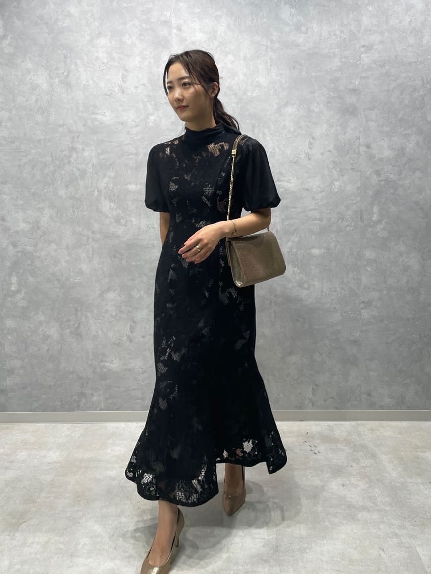 ゴールド系のパンプス、ゴールド系のクラッチバッグ、ブラック系のドレスを着用したレディースの秋コーディネートの4枚目の写真