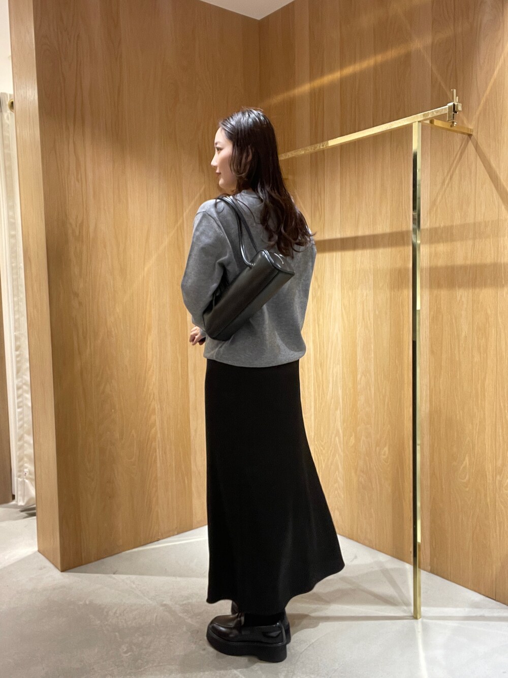 グレー系のニット/セーター、ブラック系のスカート、ブラック系のローファーを着用したレディースの秋コーディネートの5枚目の写真