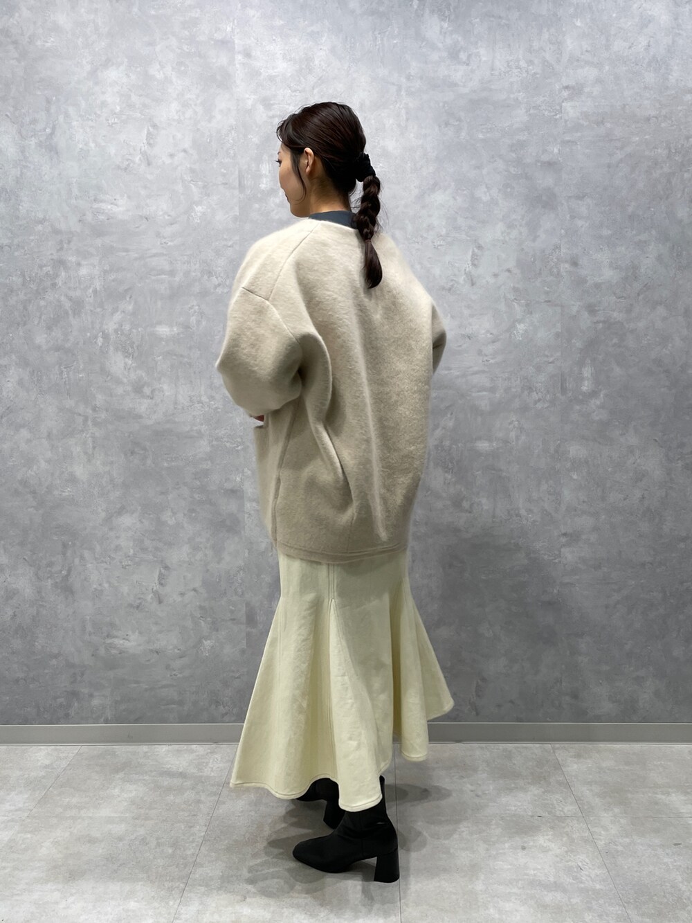 グリーン系のニット/セーター、ホワイト系のカーディガン/ボレロ、ブラック系のブーツを着用したレディースの冬コーディネートの3枚目の写真