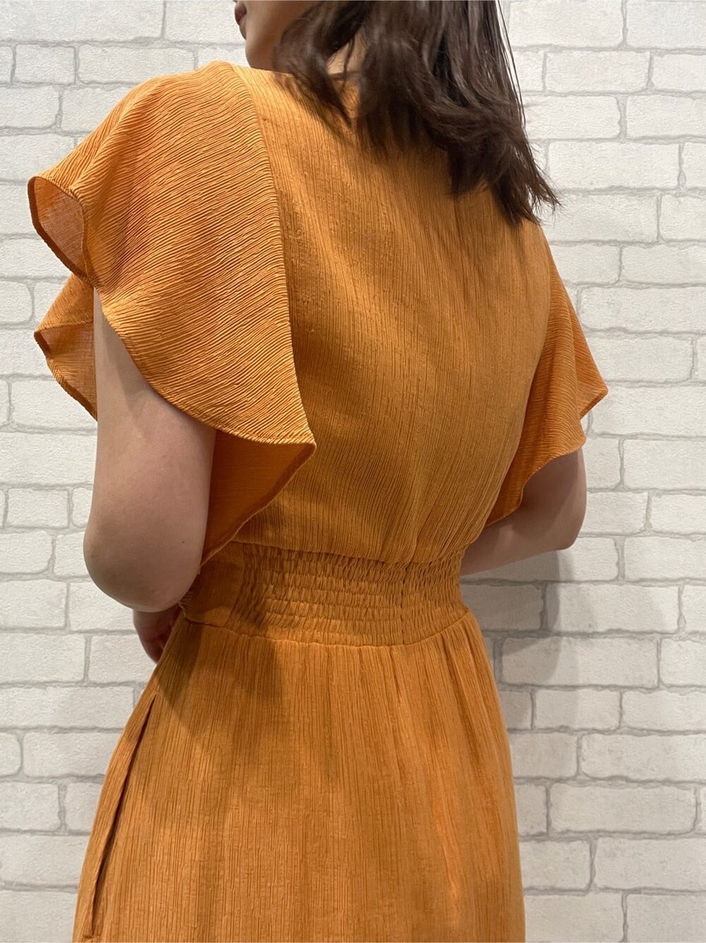 オレンジ系のワンピース、ホワイト系のサンダルを着用したレディースの春コーディネートの7枚目の写真