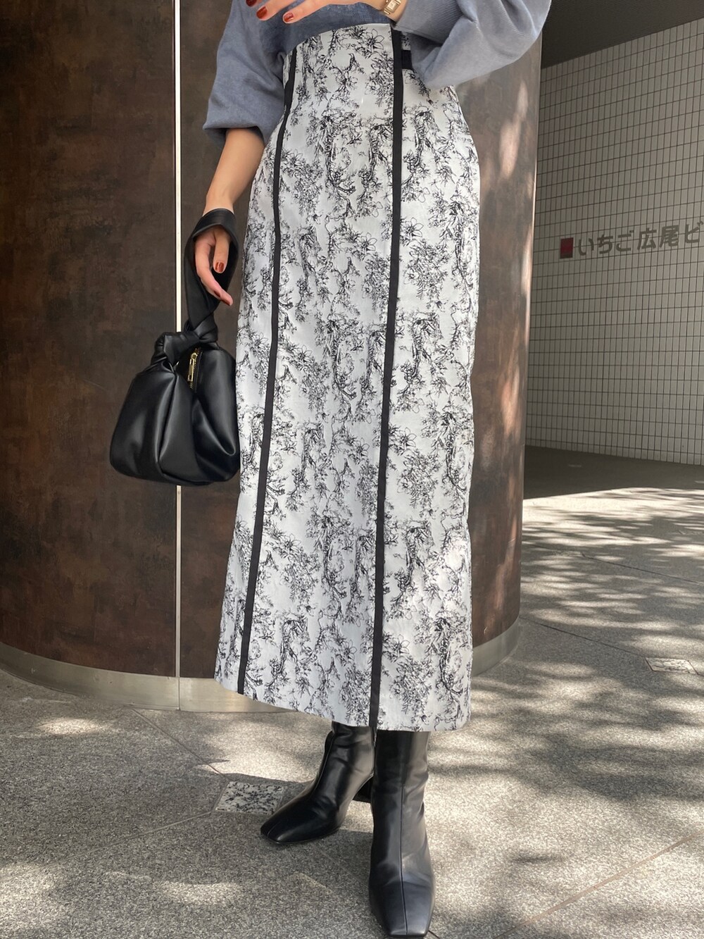 ブラック系のハンドバッグ、ブラック系のスカート、ブラック系のブーツを着用したレディースの秋コーディネートの8枚目の写真