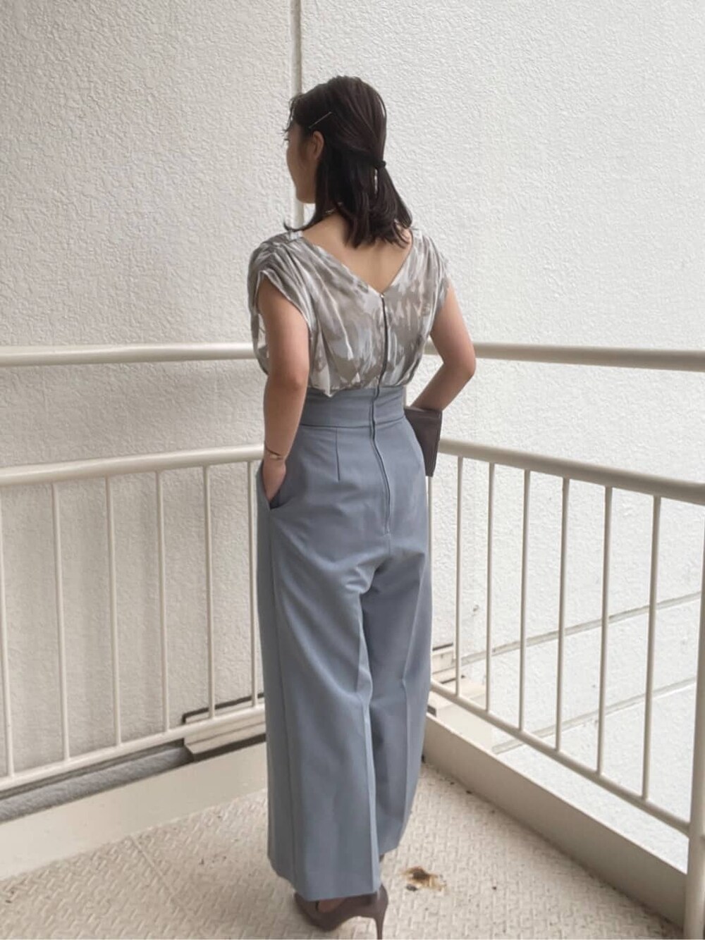シルバー系のパンプス、シルバー系のクラッチバッグ、ブルー系のパンツドレスを着用したレディースの春コーディネートの4枚目の写真