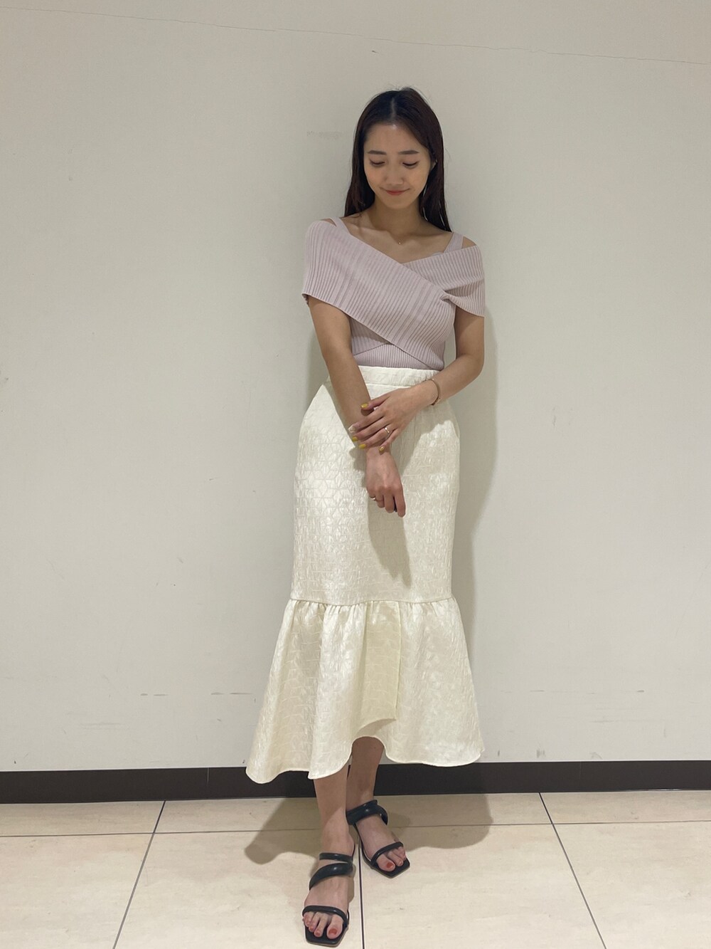 ホワイト系のスカート、ベージュ系のニット/セーター、ブラック系のサンダルを着用したレディースの春コーディネートの2枚目の写真