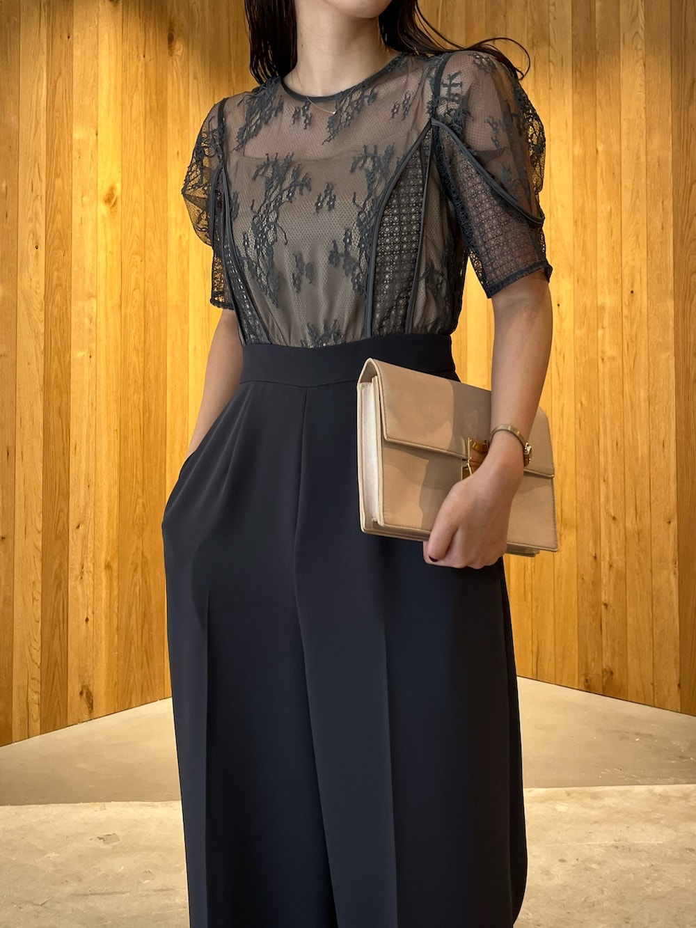 グレー系のパンツドレス、ベージュ系のクラッチバッグ、ベージュ系のパンプスを着用したレディースの冬コーディネートの5枚目の写真