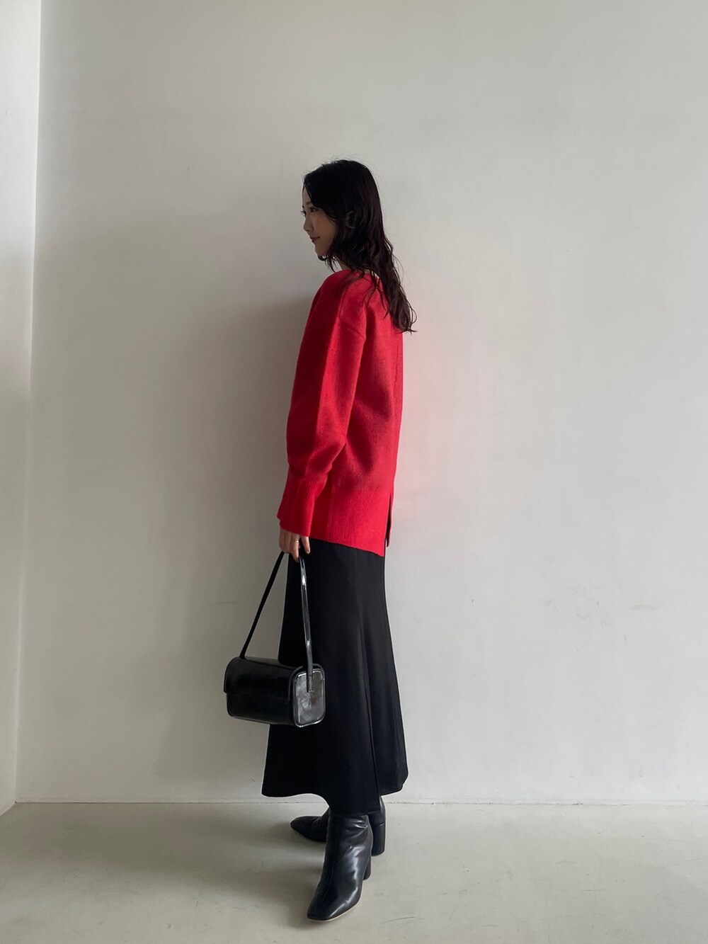 ブラック系のブーツ、ブラック系のスカート、レッド系のニット/セーターを着用したレディースの秋コーディネートの3枚目の写真