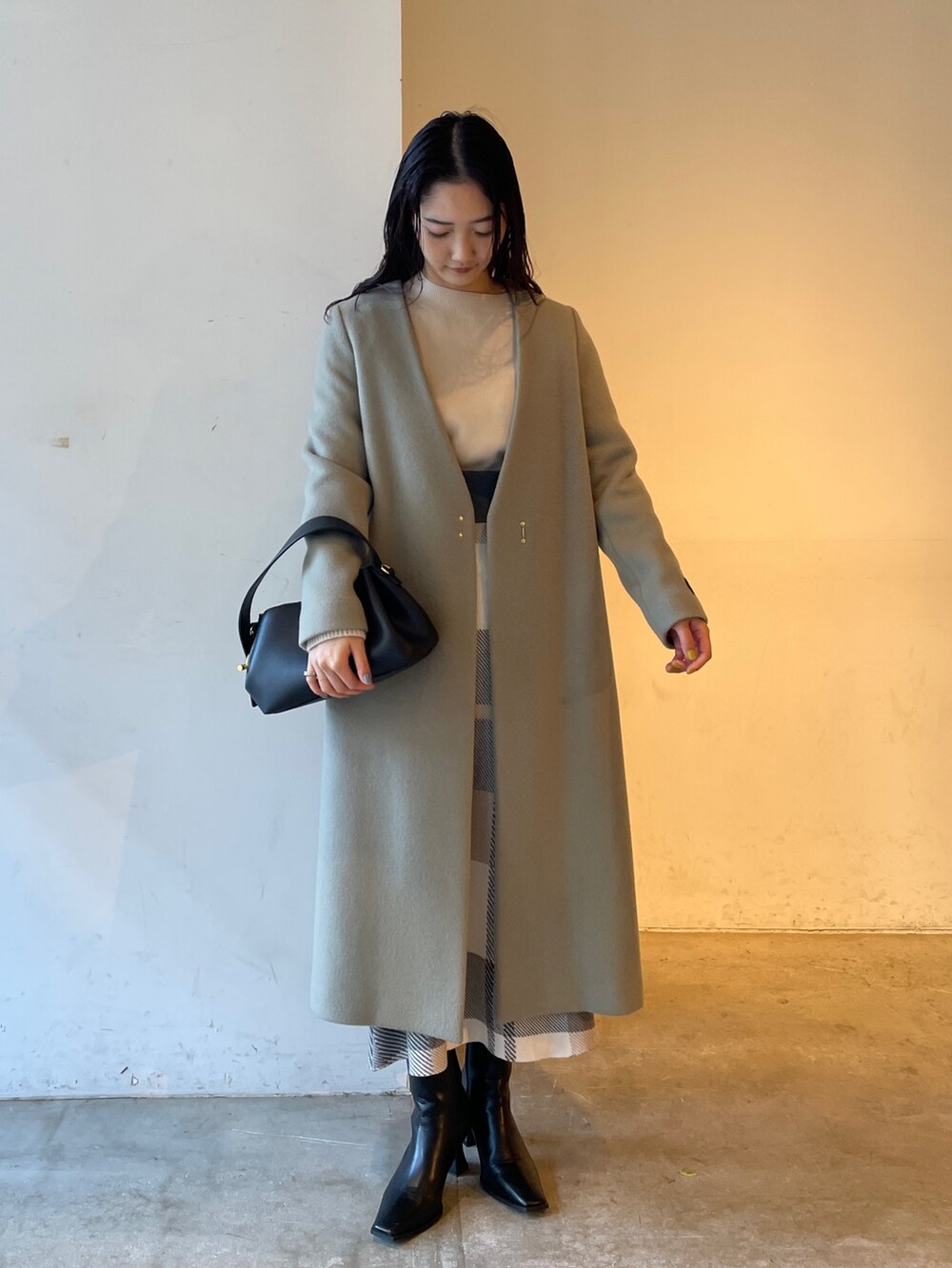 ブラック系のブーツ、ベージュ系のスカート、ホワイト系のニット/セーターを着用したレディースの冬コーディネートの6枚目の写真