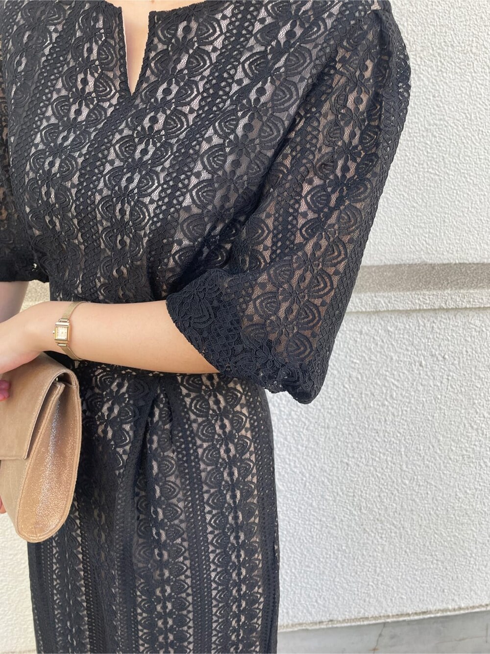 ゴールド系のパンプス、ゴールド系のクラッチバッグ、ブラック系のドレスを着用したレディースの冬コーディネートの6枚目の写真