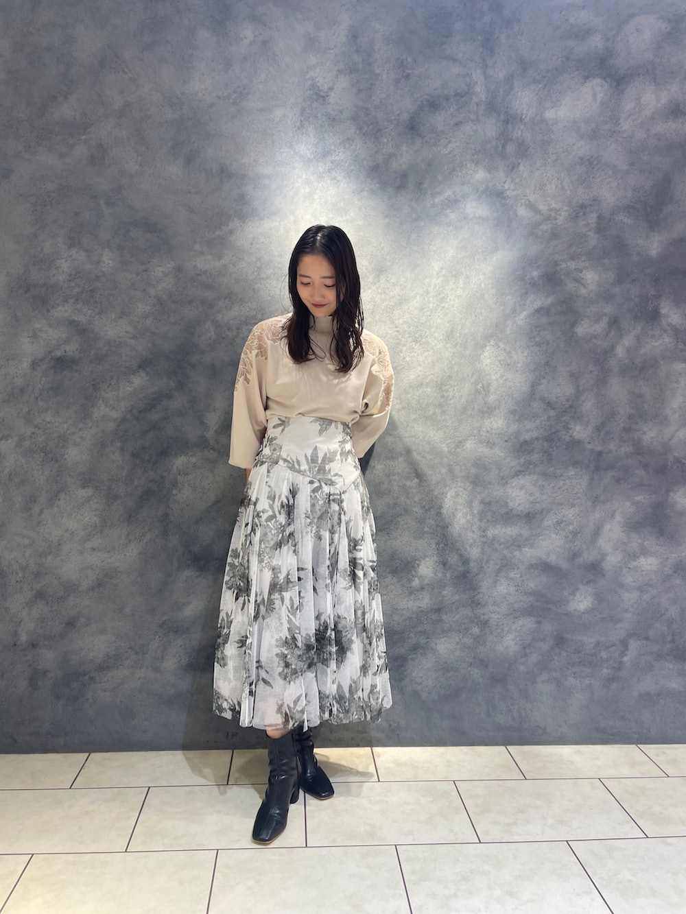 ホワイト系のニット/セーター、ブラック系のブーツ、ブラック系のスカートを着用したレディースの秋コーディネートの2枚目の写真